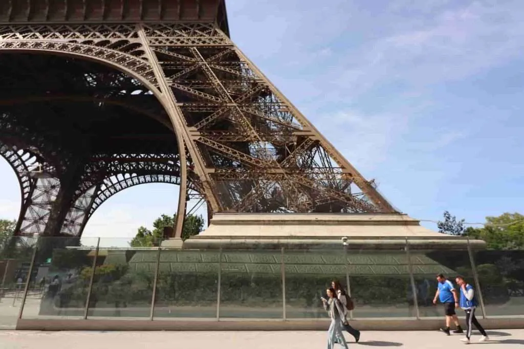 Visitors walking near the base and foundation of the Eiffel Tower in Paris